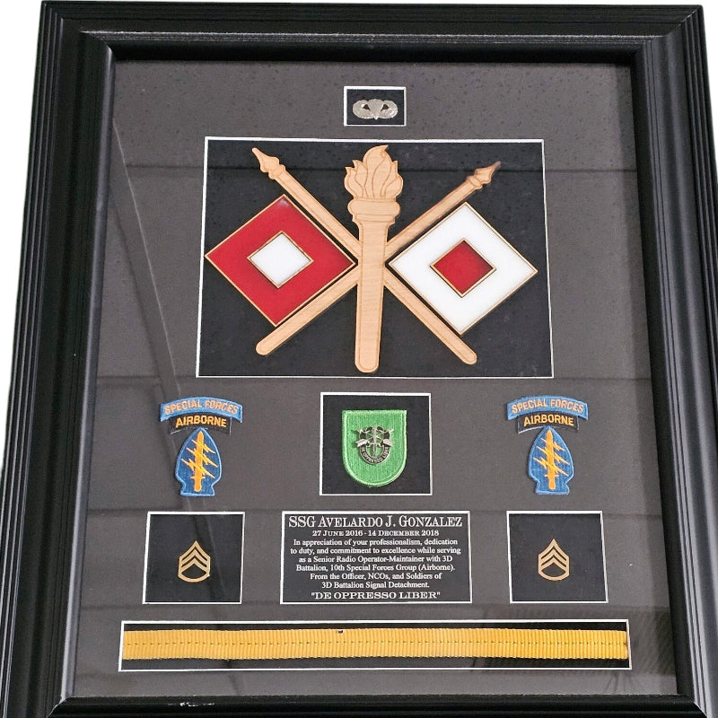Framed military memorabilia with badges, ribbons, and a black background