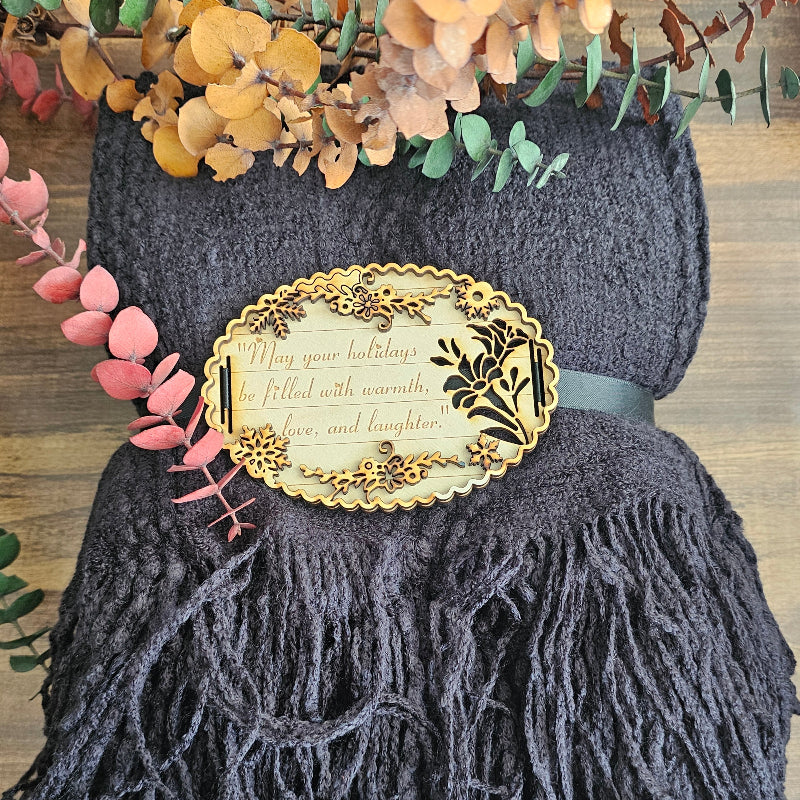 Dark gray yarn with decorative label and tassels on a wooden surface with floral elements.