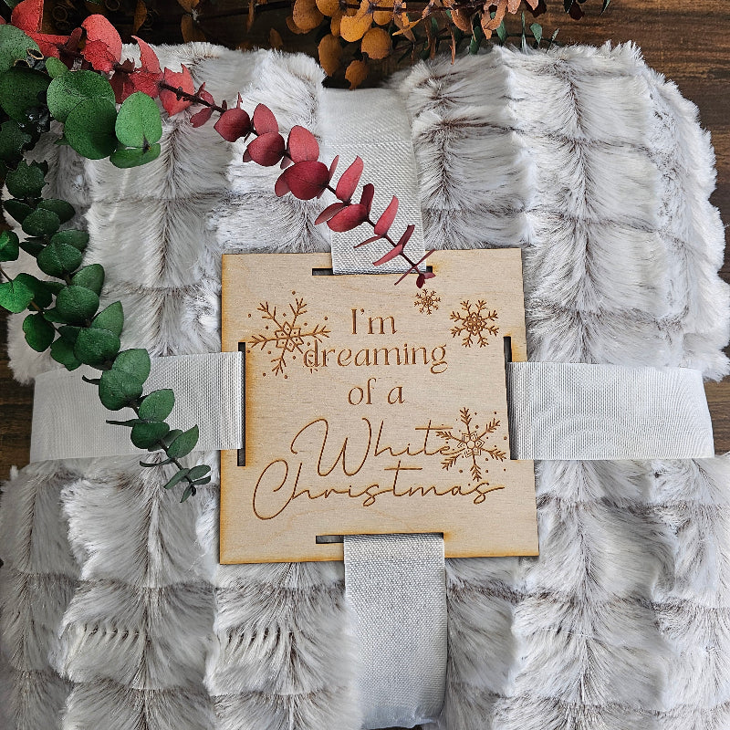 Decorative gift with 'I'm dreaming of a White Christmas' card on a textured surface with foliage.