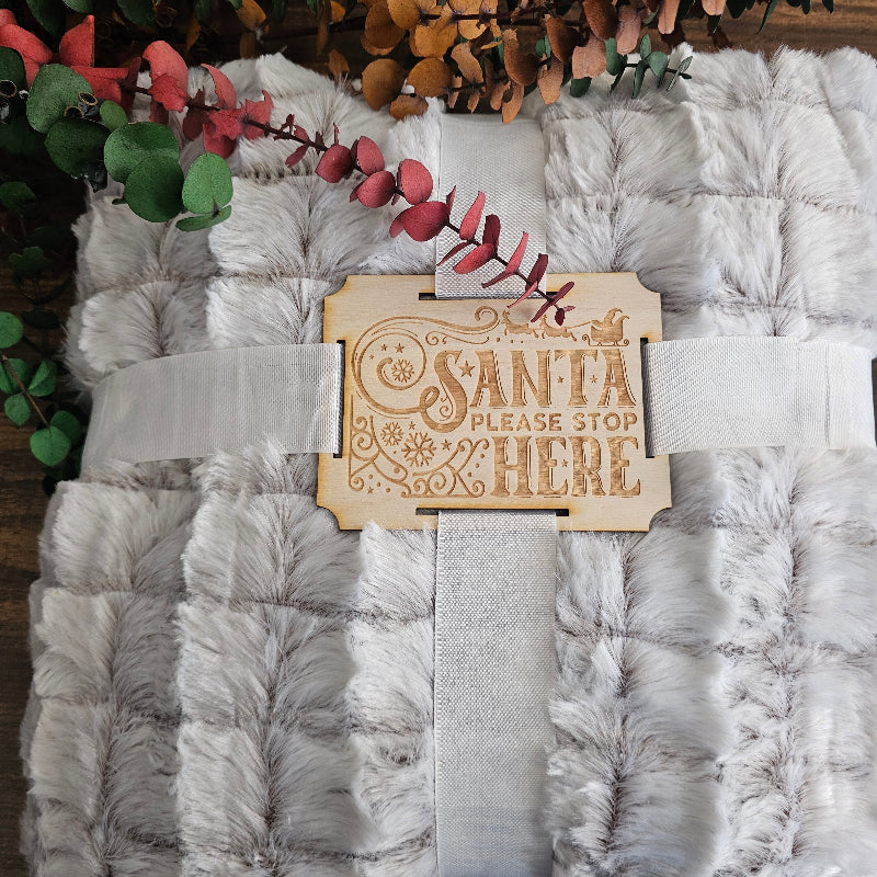 Stack of gray textured towels with a decorative wooden sign on a wooden surface.