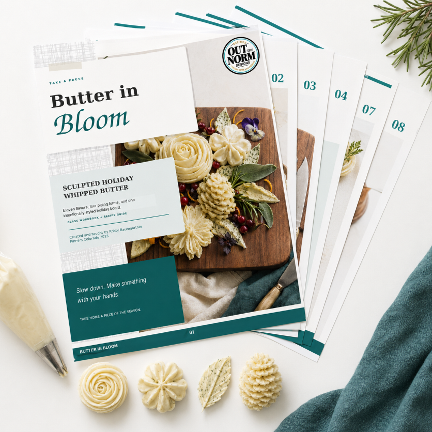 A flat-lay of an Out-Norm baking recipe book titled 'Butter in Bloom' surrounded by piped butter decorations, numbered recipe cards, and a piping bag on a white surface.