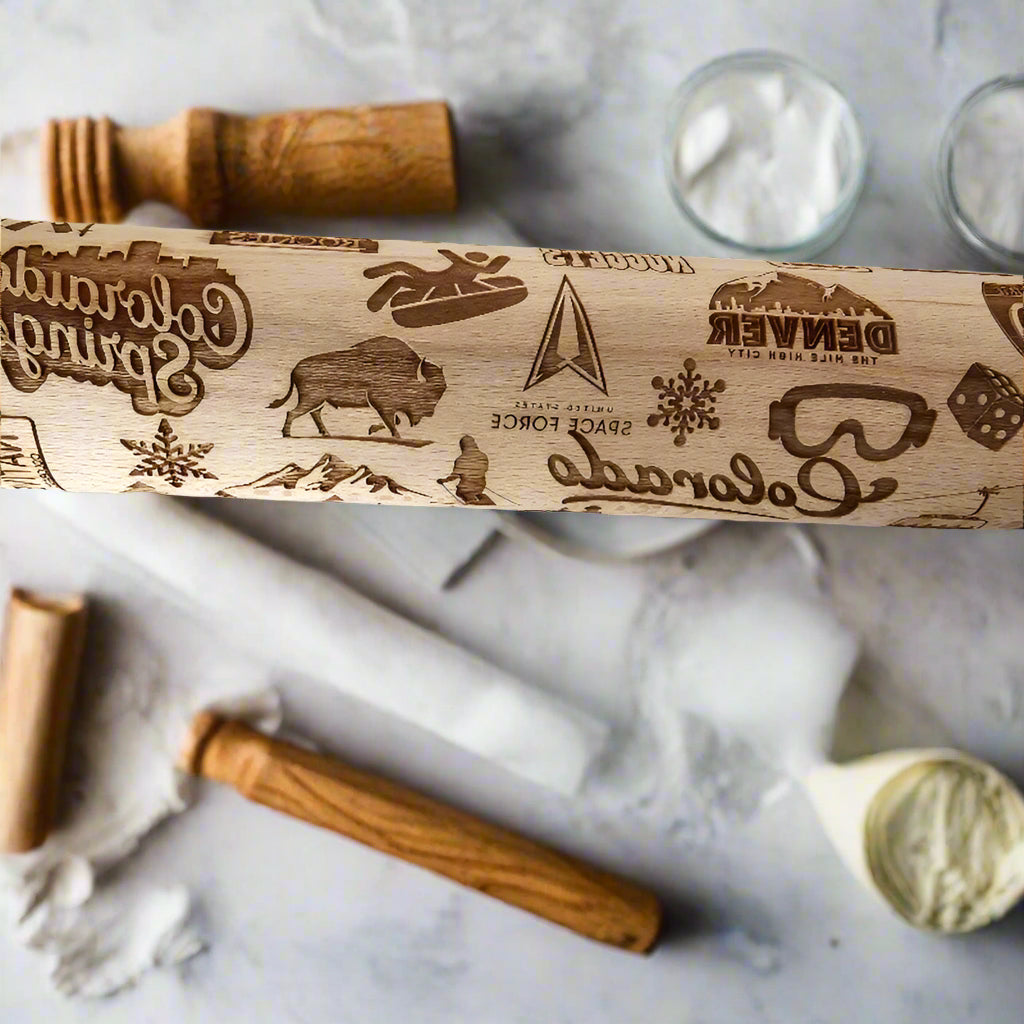 Wooden rolling pin with engraved designs on a marble surface
