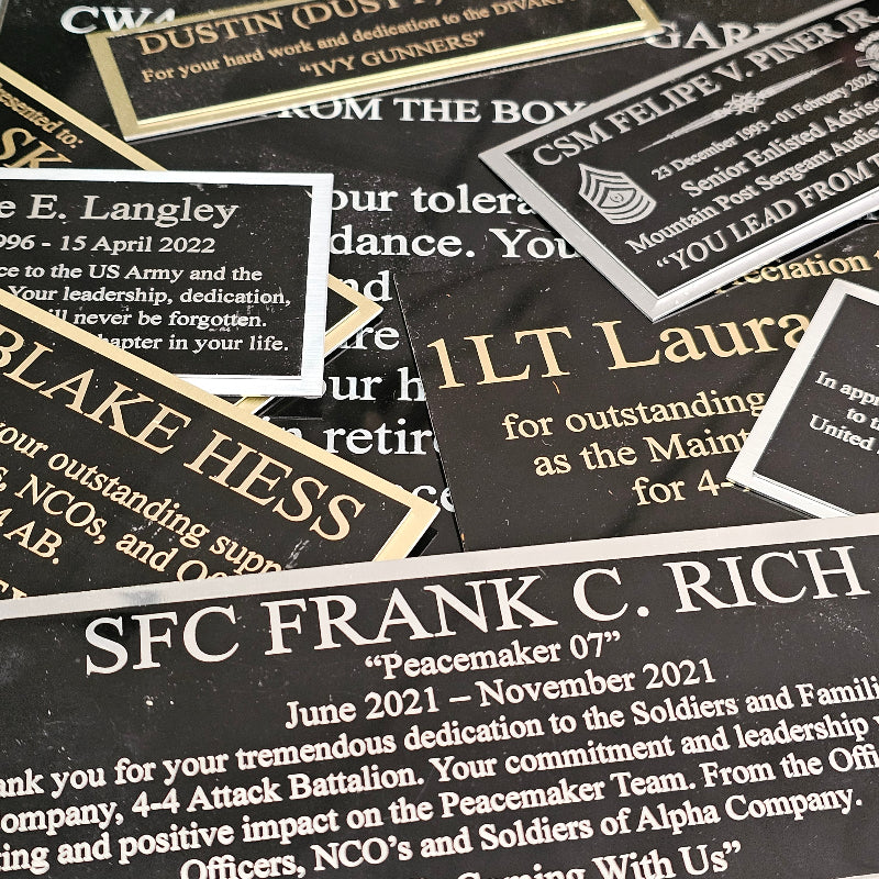 Collection of military commendation plaques with engraved names and dates.