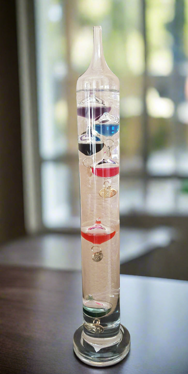 Glass thermometer with colored liquid on a beige surface