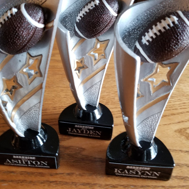 Three football-themed trophies on a wooden surface