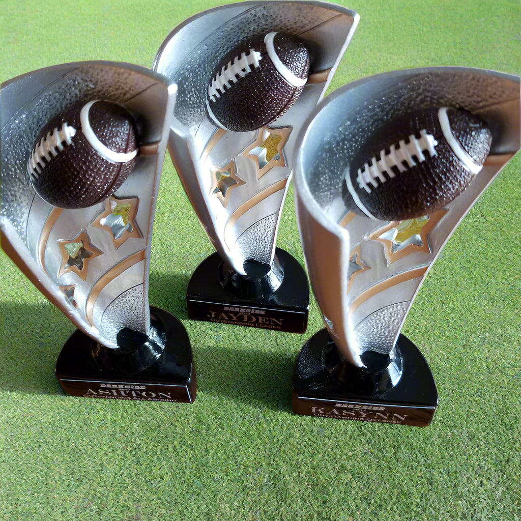 Three football-themed trophies on a wooden surface
