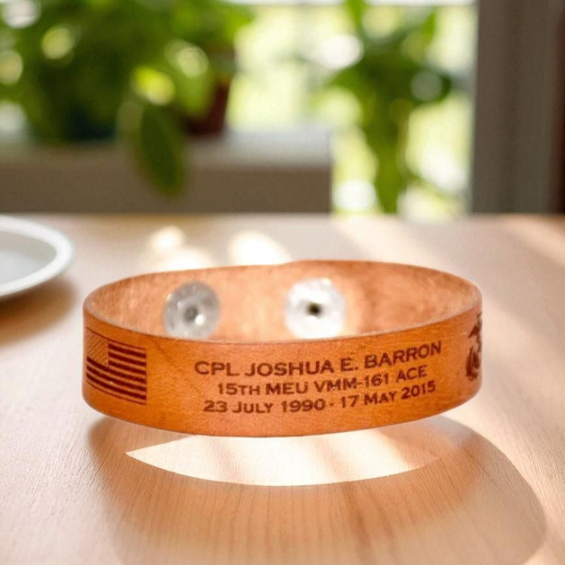 Leather Memorial bracelet with engraved text on a wooden surface with plants in the background