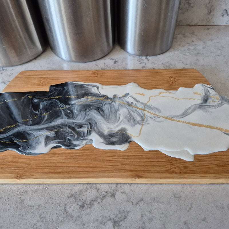 Wooden cutting board with a marble-like design on a countertop