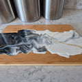 Wooden cutting board with a marble-like design on a countertop
