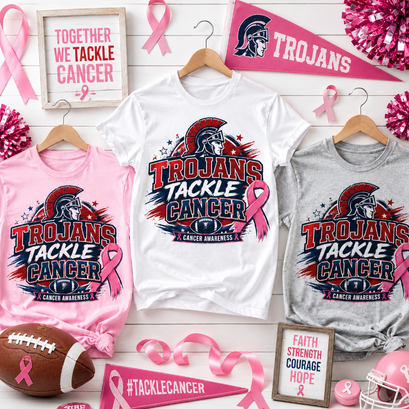 Three T-shirts in white, pink, and heather gray, each printed with a large 'TROJANS TACKLE CANCER' graphic featuring a Spartan helmet, football, and pink ribbon. The shirts are displayed on wooden hangers on a white wood plank background, surrounded by pink ribbons, a football, a pink pennant, and framed quotes.