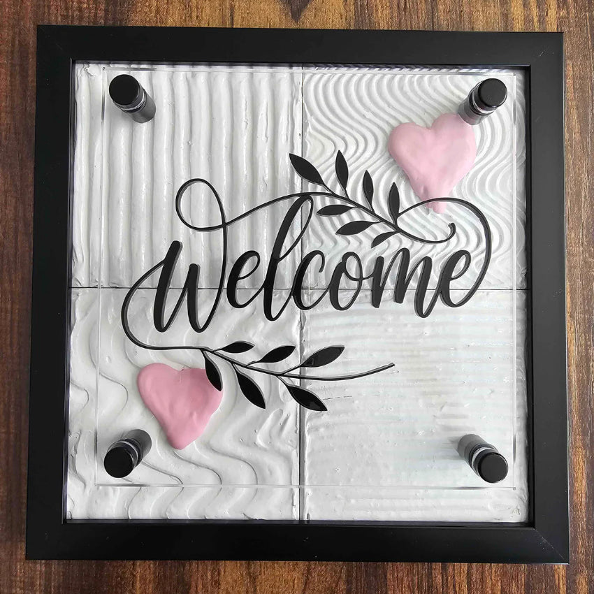 Decorative sign with 'Welcome' text and hearts on a wooden background