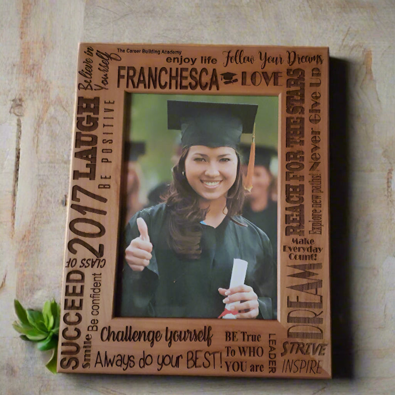 Wooden frame with text and a photo of a person holding a diploma on a wall.