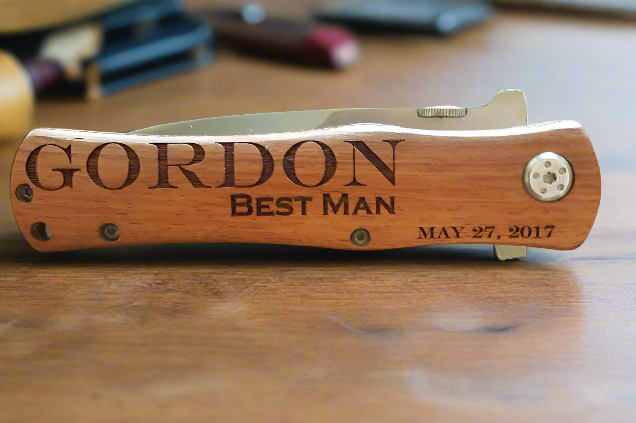 Personalized wooden pocket knife with engraved text on a wooden surface.